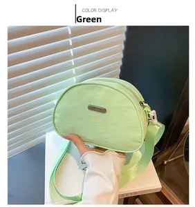 Detail view of a light green nylon crossbody bag featuring a branded metal nameplate