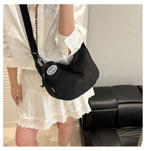 Detail of a black nylon crescent tote bag with adjustable strap and small round pouch