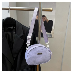 Detail of purple nylon crescent bag featuring a metal logo and adjustable wide strap