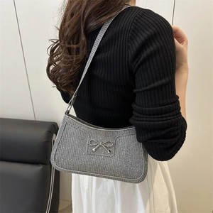 Silberne Glitzer-Schultertasche mit Metallschleife am Model in stilvoller Umgebung