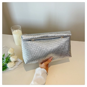 Close-up of the silver woven texture on a minimalist envelope clutch with a metal finish