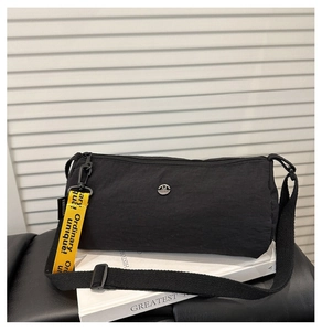 Detailaufnahme der schwarzen Zylindertasche aus Nylon mit gelbem Slogangurt vor weißem Hintergrund