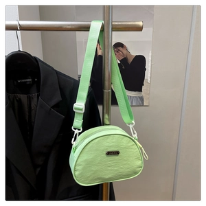 Close-up of light green nylon crossbody bag with metal logo and white plastic hook