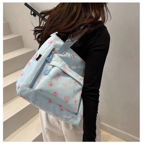Macro view of light blue floral canvas backpack with sweet bow prints and triangle zipper