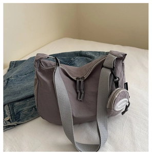 Detail of grey-purple nylon crescent bag with wide strap and round coin purse attachment