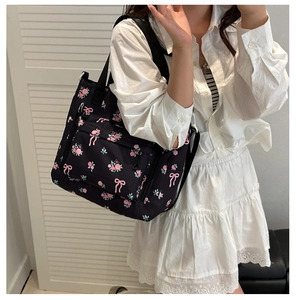 Close-up of black shoulder bag with pink floral and bow prints on high-quality nylon fabric