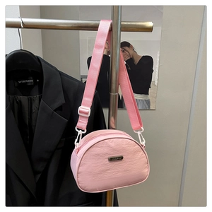 Pink nylon dumpling bag with adjustable wide strap shown on a showroom display