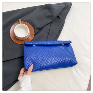 Detail shot of the royal blue woven leather texture on a stylish envelope clutch bag
