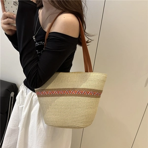 Große Strohtasche mit buntem Boho-Band und braunen Ledergriffen für den Sommerurlaub
