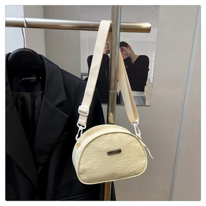 Detail of beige crescent nylon bag with wrinkled texture and JING PIN metal nameplate