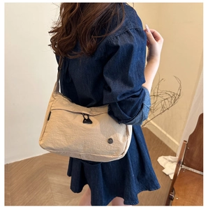 Side view of beige minimalist nylon shoulder bag shown on model for size and fit