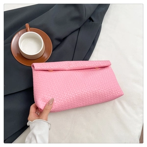 Detailed texture of pink woven pattern envelope clutch bag held in hand for summer fashion