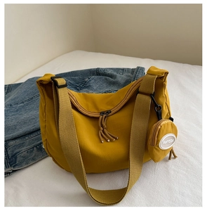 Detail of mustard yellow nylon crescent bag with round coin purse on a denim background