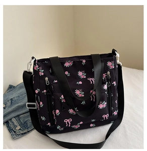 Close-up of black floral tote bag featuring pink rose patterns and adjustable strap