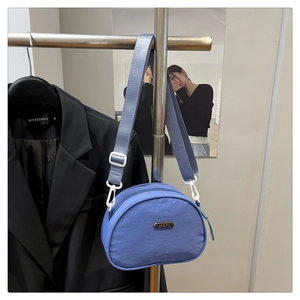 Detail of blue nylon crossbody bag with adjustable wide strap and metallic logo plate