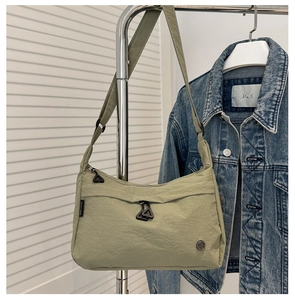 Detail of sage green nylon crossbody bag with metal logo and triangle zipper pull