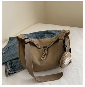 Close-up of khaki nylon tote bag with adjustable strap and mini round coin purse charm