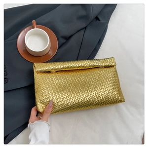 Detail of gold woven rectangle clutch bag with glossy metallic finish and flap closure