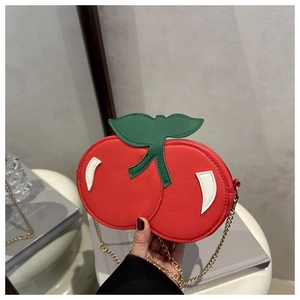 Detailed macro view of cherry-shaped mini crossbody bag with gold chain strap