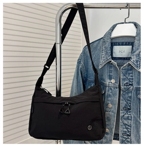 Detailed close-up of a black nylon crossbody bag featuring dual zippers and durable texture
