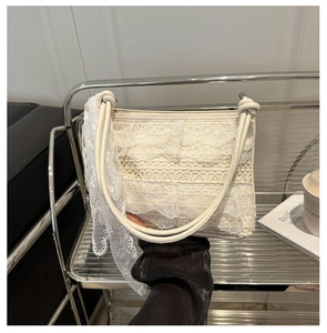 Detail of cream lace tote bag with silk scarf on handle against a modern background