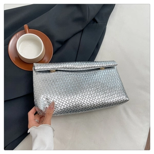 Silver woven envelope clutch bag with gold buttons on a dark fabric background