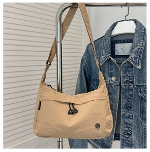 Detail view of khaki nylon crossbody bag featuring adjustable drawstring and woven logo label