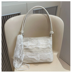 Detail of white lace crossbody bag featuring layered ruffles and ribbon shoulder strap