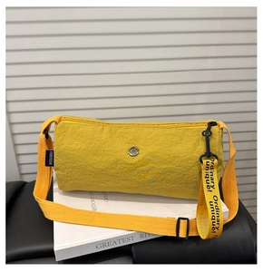 Makro-Detail der gelben Nylon-Zylindertasche mit Metall-Logo und Web-Anhänger