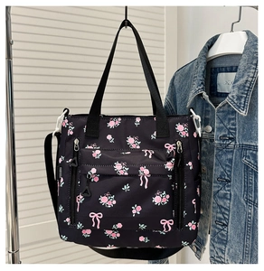 Detail of black floral tote bag with pink patterns showing adjustable shoulder strap