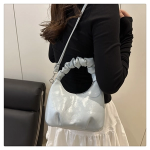 Detail of light blue pleated hobo bag with cloud-shaped handle and silver hardware