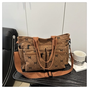 Detail of brown corduroy tote bag showing multiple zipper pockets and bow lattice patterns