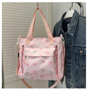 Detail of floral tote bag showing pink ribbon patterns and functional multi-zipper pockets