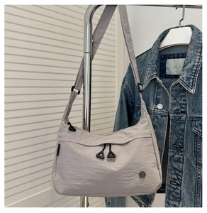 Detail of light grey hobo bag showing nylon texture and front zipper compartments