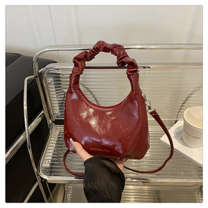Close-up of dark red dumpling bag with ruched handle and fashion text logo