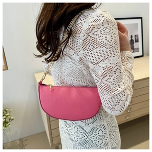Detail der pinkfarbenen Satteltasche mit goldener Kette und strukturierter Lederoptik