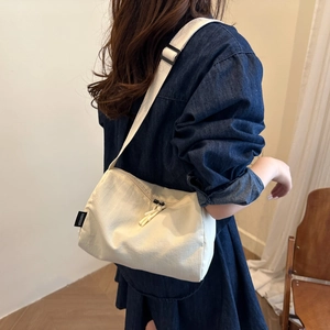 Minimalist beige nylon crossbody bag featuring a large capacity and adjustable strap