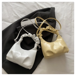 Detail view of stylish pleated crossbody bags in white and yellow with fashion lettering