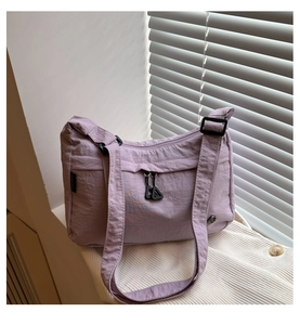 Detail of lavender nylon shoulder bag with zipper pocket on white striped fabric