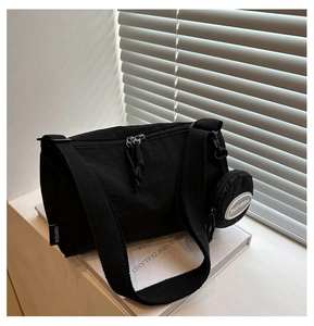 Nahaufnahme der schwarzen Nylon-Zylindertasche mit kleiner Münztasche und breitem Gurt