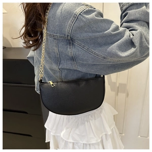 Seitenansicht eines Modells mit schwarzer Halbmond-Satteltasche aus Leder und goldener Kette