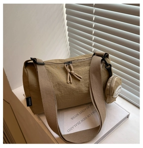 Detail der khakifarbenen Nylon-Zylindertasche mit rundem Mini-Beutel auf einem Buch