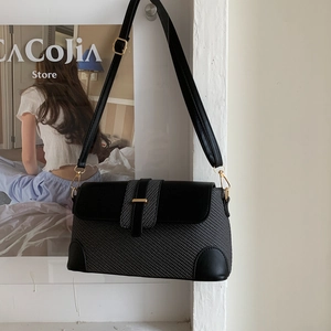 Détail d'un sac à bandoulière en cuir noir et tissu tressé gris avec boucles dorées