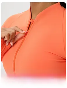 Close-up of bright orange yoga jacket featuring stand collar and functional thumb holes