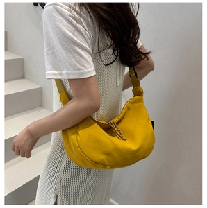 Detail of a bright yellow nylon crescent crossbody bag with adjustable strap and zipper