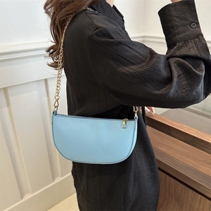 Minimalist light blue saddle bag in pebble leather with a gold chain strap for women