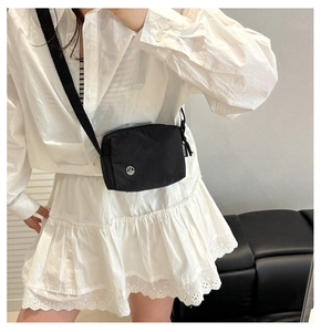 Close-up of black nylon crossbody bag featuring a silver M logo and adjustable strap