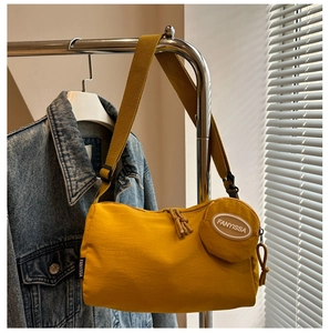 Detail van de gembergele nylon draagtas met kleine ronde portemonnee en brede riem
