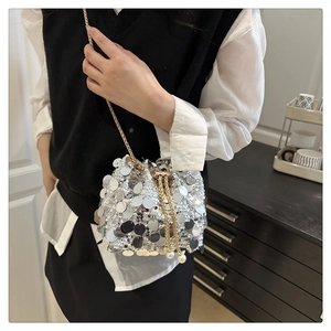 Detail of silver sequin bucket bag with gold chain strap and pearl drawstring closure
