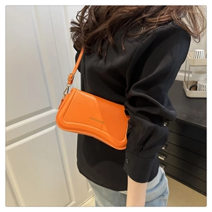Detailed view of the orange shoulder bag with Fashion & Bags lettering on leather